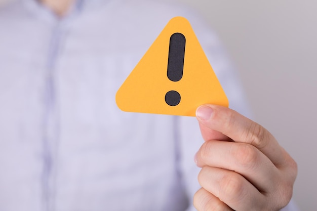 man holding a yellow triangular warning sign