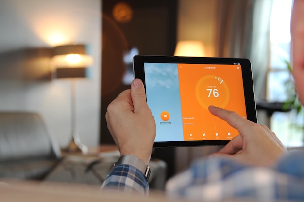 man is adjusting a temperature using a tablet with smart home app in modern living room