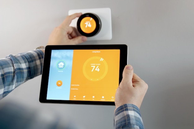 man is adjusting a temperature using a tablet with smart home app in modern living room