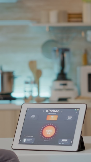 Man looking at tablet with intelligent software placed on kitchen table controlling light with high tech application.
