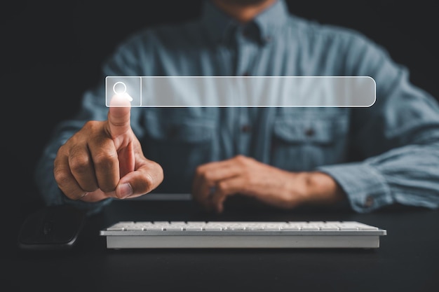 Man's finger pointing at search icon on a dark background using a computer keyboard for search engine optimization Browsing internet data networking and searching concept is displayed