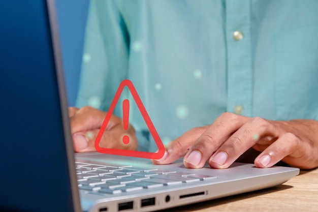 Man using a laptop with red triangle caution warning sign for notification error