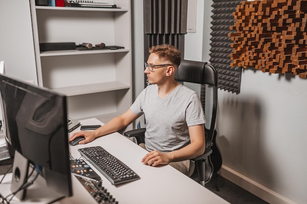 Man working in music studio using computer wearing glasses Sound engineer working and mixing track Programmer watching at display of it while listening music Technology concept