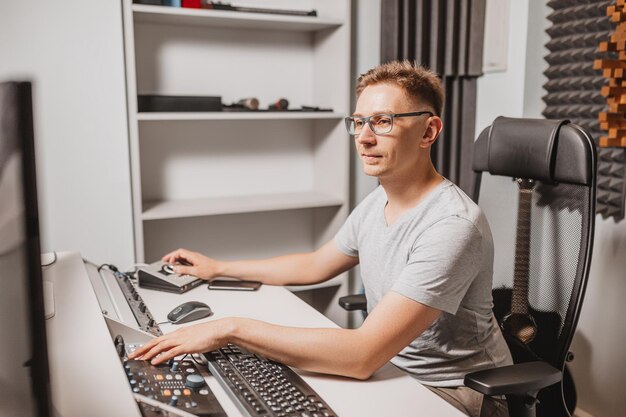 Man working in music studio using computer wearing glasses Sound engineer working and mixing track Programmer watching at display of it while listening music Technology concept