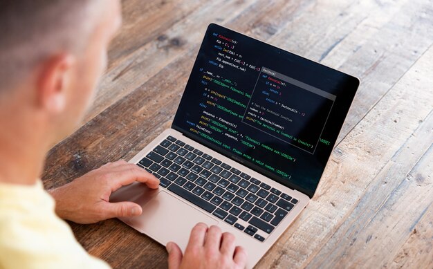 Man writing computer code on laptop