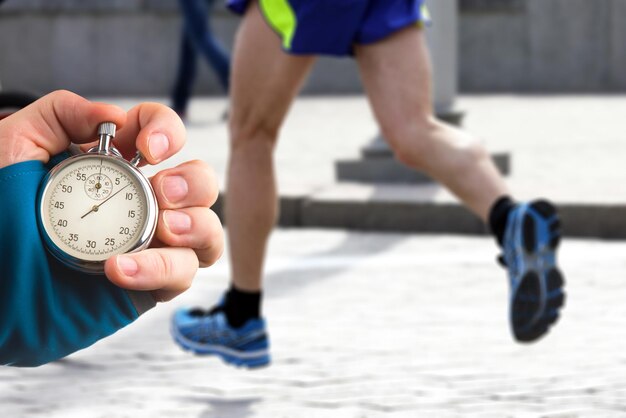 measuring the running speed of an athlete using a mechanical stopwatch hand with a stopwatch on the background of the legs of a runner
