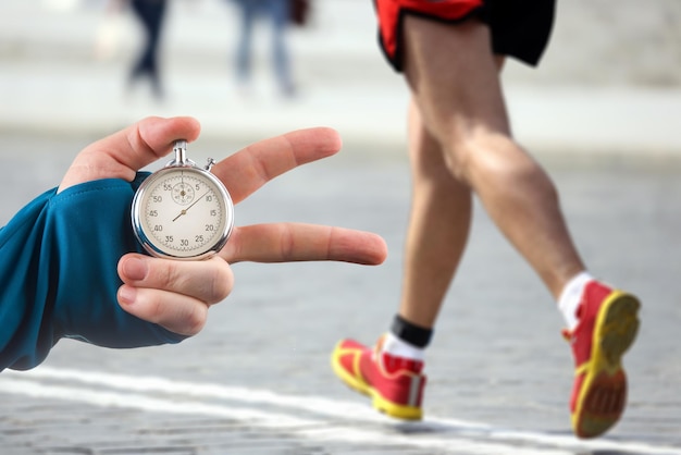 measuring the running speed of an athlete using a mechanical stopwatch hand with a stopwatch on the background of the legs of a runner