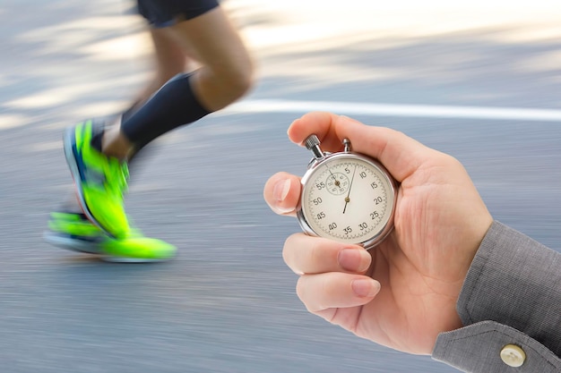 measuring the running speed of an athlete using a mechanical stopwatch hand with a stopwatch on the background of the legs of a runner