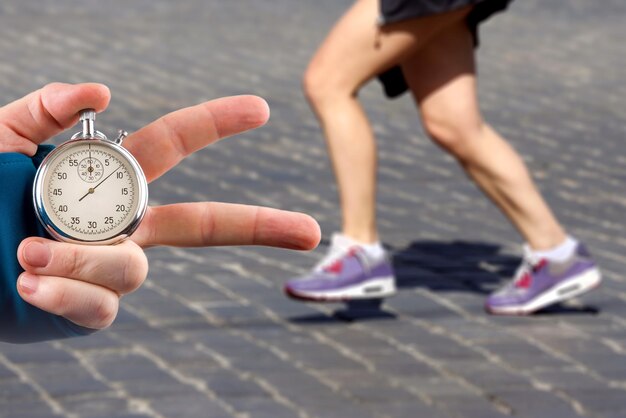 measuring the running speed of an athlete using a mechanical stopwatch hand with a stopwatch on the background of the legs of a runner