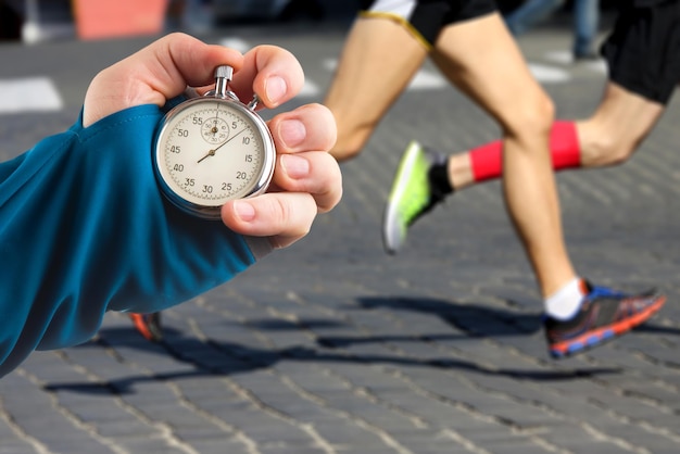 measuring the running speed of an athlete using a mechanical stopwatch hand with a stopwatch on the background of the legs of a runner
