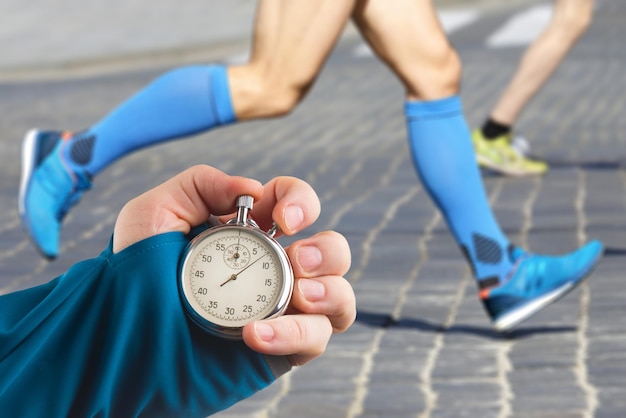 measuring the running speed of an athlete using a mechanical stopwatch hand with a stopwatch on the background of the legs of a runner