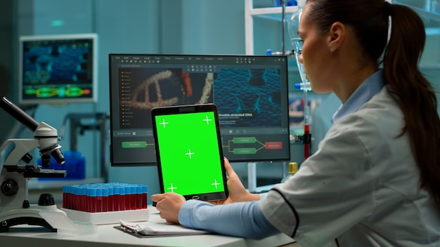Medical research laboratory portrait of female scientist holding tablet with green chroma key screen. Advanced scientific lab for medicine, biotechnology working for vaccine development.