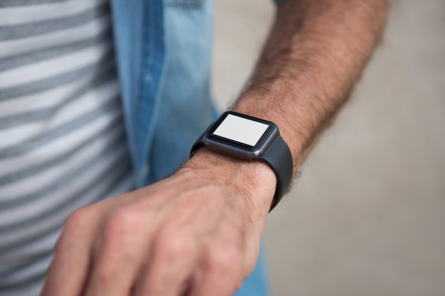 mid section of man wearing smartwatch on beach