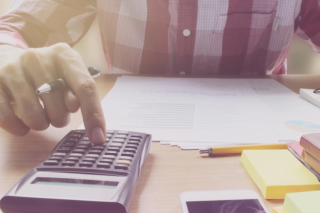 Midsection of businessman using smart phone at table in office