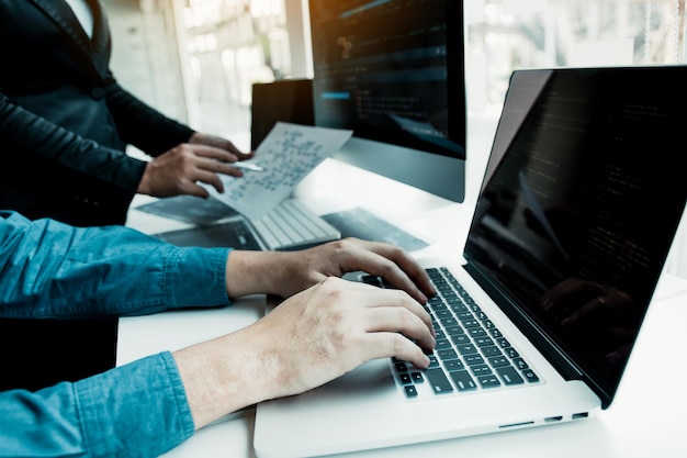 Midsection of businesswoman showing paper with coworker using laptop