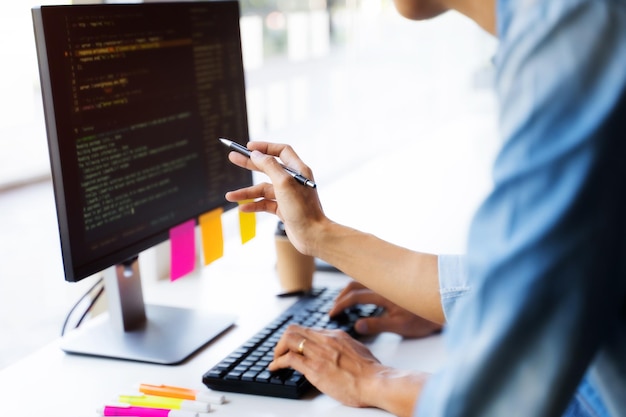 Midsection of colleagues coding over computer in office