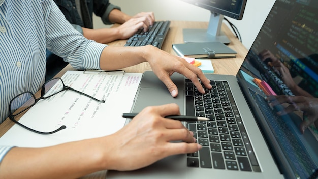 Midsection of colleagues using laptop on desk in office