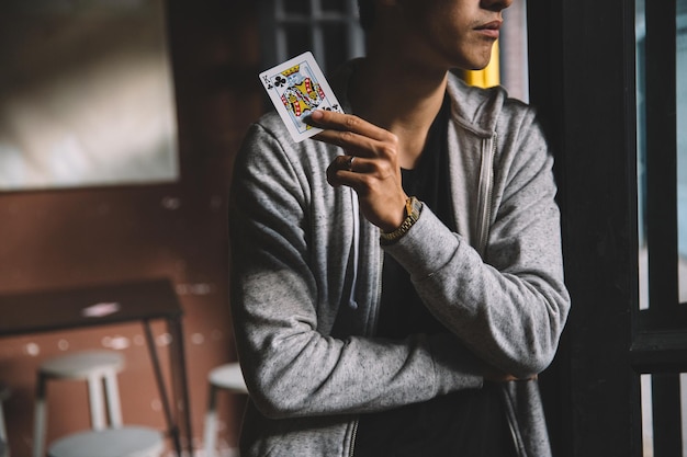midsection of man standing with king of clubs by door