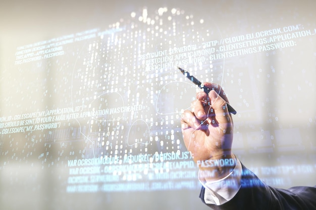 Miehen käsi kynällä työskentelee abstraktin virtuaalisen luovan koodikallon hologrammin kanssa sumealla toimistotaustalla, henkilötietojen varkauden ja haittaohjelmien konsepti, monivalotus
