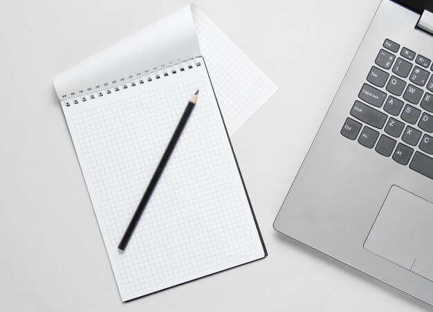 Minimalistic business concept. Laptop, notebook with pencil on white