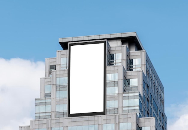 Mock up white vertical large LED display billboard on tower building with blue sky background clipping path for mockup
