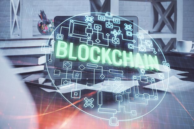 Monivalotus blockchain-teeman hologrammista ja pöydästä tietokoneen taustalla. Bitcoin-kryptovaluutan konsepti