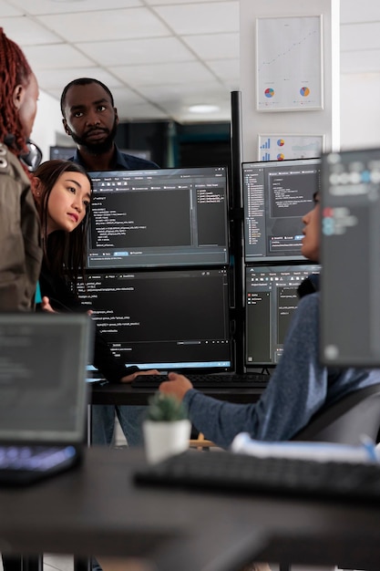 Multi ethnic engineers analyzing server code and database, brainstorming program ideas to develop new security system. Programmers working with coding language collaborating on group project.