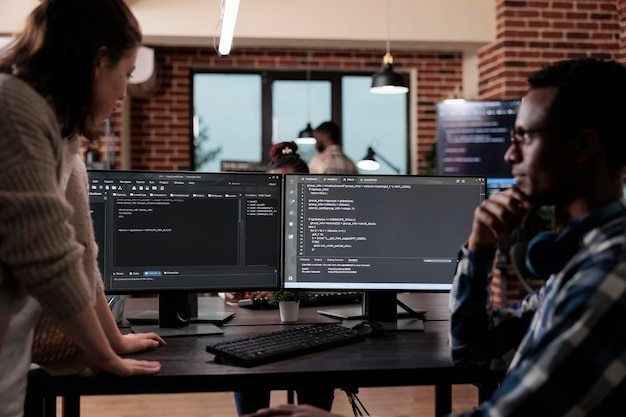 Multiethnic cyber security team members in agency office writing cloud database processing algorithm. Software developers sitting at desk and developing a functional data encryption system.