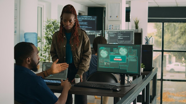 Multiethnic group of program coders dealing with hacked it system, not having access to use database on computer. Trying to solve hacking issue and work on firewall security server.