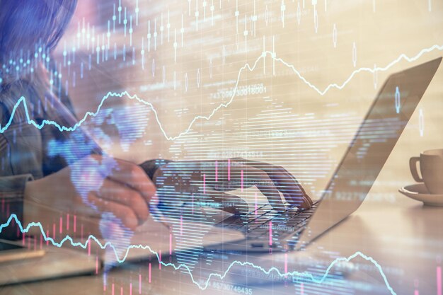 Näkymä, jossa liikenaisen kädet näkyvät kirjoittamassa tietokoneella ja forex-graafin hologrammi piirtää. Taloudellisen analyysin konsepti