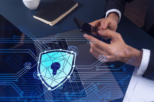 Ohjelmoija selaa Internetiä älypuhelimella suojellakseen kyberturvallisuutta hakkerihyökkäyksiltä ja tallentaakseen asiakkaiden luottamuksellisia tietoja. Lukko Hologram-kuvakkeet kirjoittavien käsien yllä. Muodollinen asu