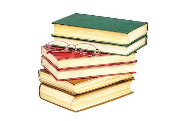 On a white surface is a pile of books and reading glasses