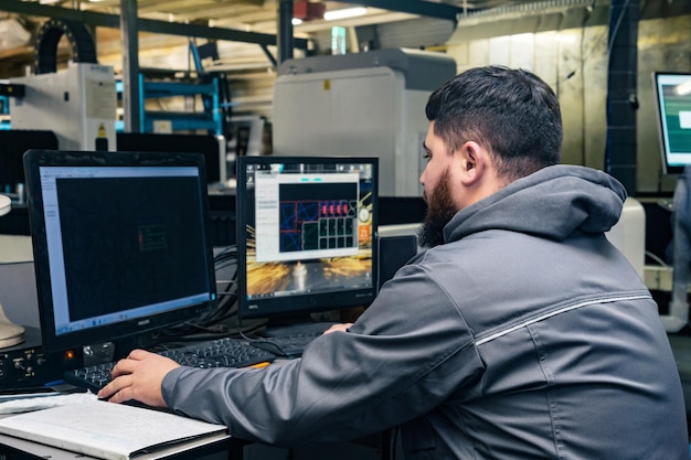 Operator controls the industrial machine while sitting in front of the monitors