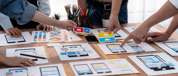 Panorama shot of frontend developer team brainstorming UI and UX designs for mobile app on paper wireframe interface User interface development team planning for userfriendly UI design Scrutinize