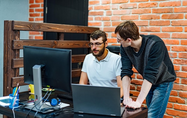 People working and communicating Two confident young men looking at laptop monitor