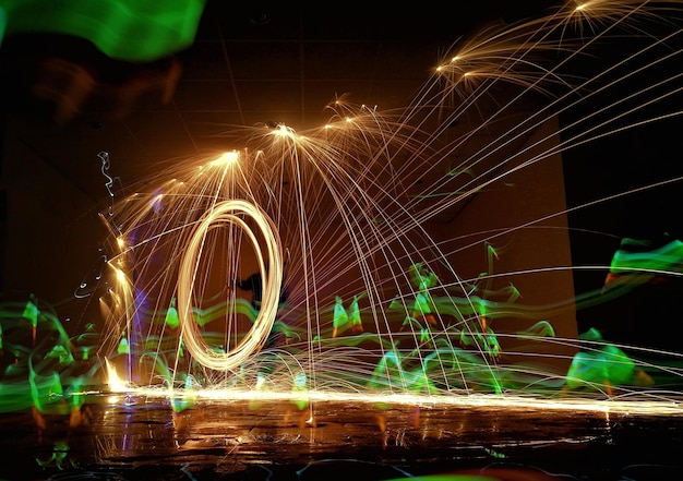 Person with spinning wire wool on street at night