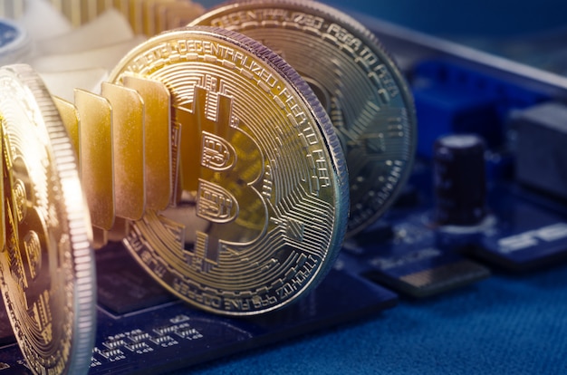 Physical Gold Bitcoin Coin on a computer video card. New independent worldwide cryptocurrency.