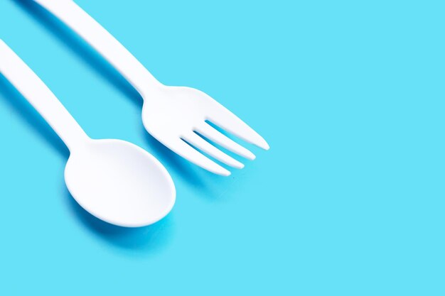 Plastic fork and spoon on blue background