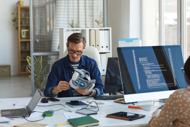 portrait of male software engineer holding vr headset while working on augmenter reality applications, copy space