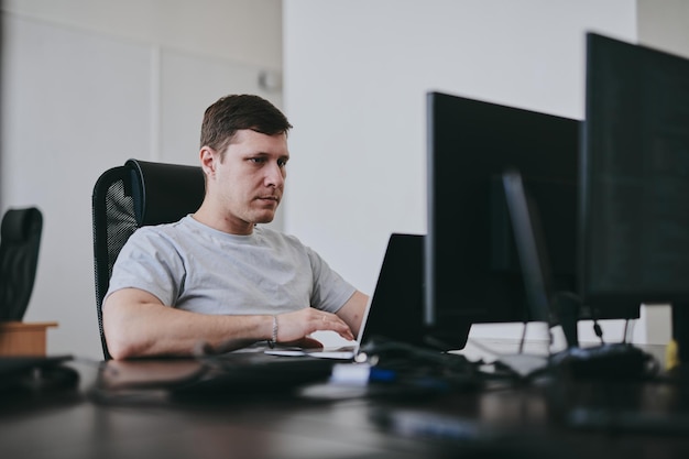 Portrait of young Caucasian male programmer working with laptop in office software developer IT technology