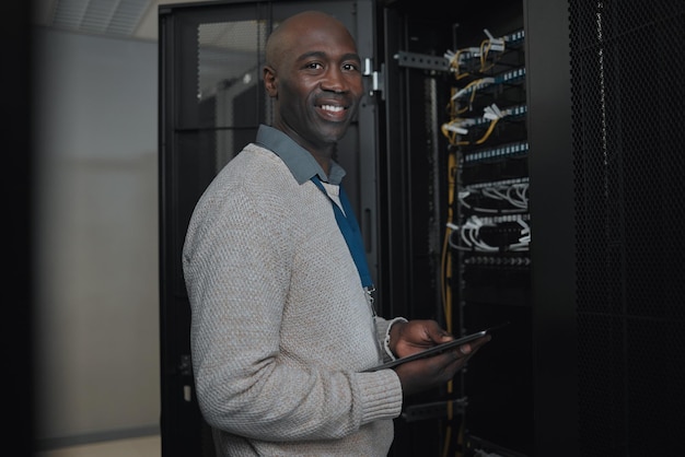 Portrait server room and IT black man on tablet for database connection cable maintenance or software update Cybersecurity face and male coder with technology for networking in data center