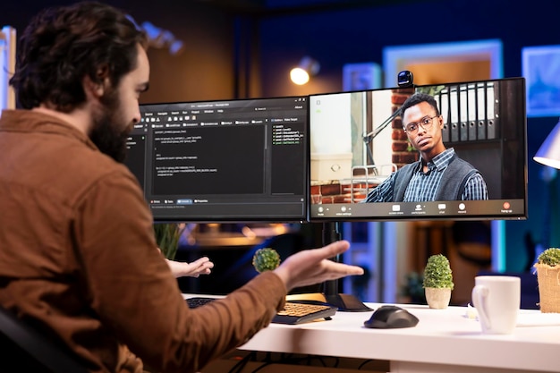Programmer doing software debugging helped by coworker in videocall