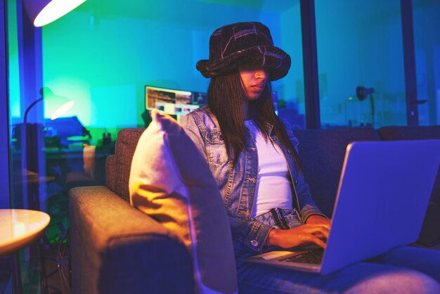 Programmer hacker and woman typing on laptop in home at night in neon light to hack software Cybersecurity ransomware phishing and female coder coding on computer for hacking database with malware