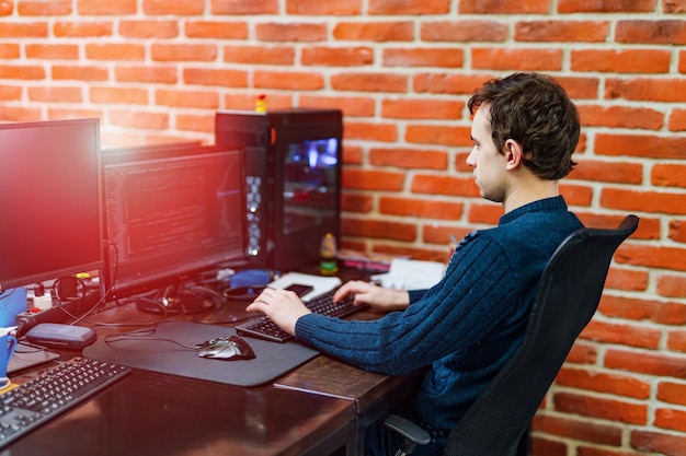 Programmer is working in a software developing company office Young man looking at computer monitor while working at computer programming Website design