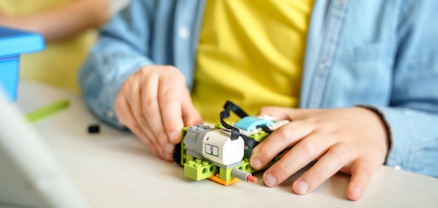 Programming work learning robotics in elementary school Children students assembly launch coding of robot Constructor parts by instructions in tablet STEM education science engineering class