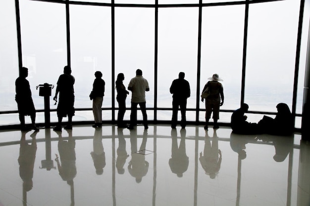 Rear view of people looking through windows in building