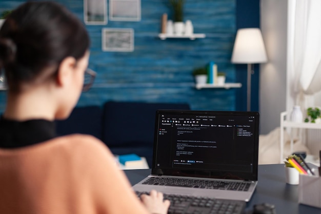 Rear view of woman using laptop at home