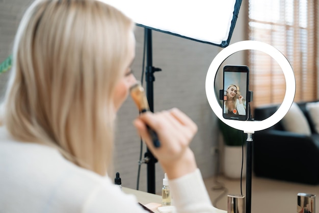 Rear view young woman making beauty and cosmetic tutorial video Blithe
