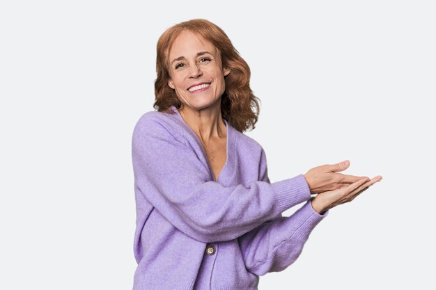 redhead midaged caucasian woman in studio holding a copy space on a palm