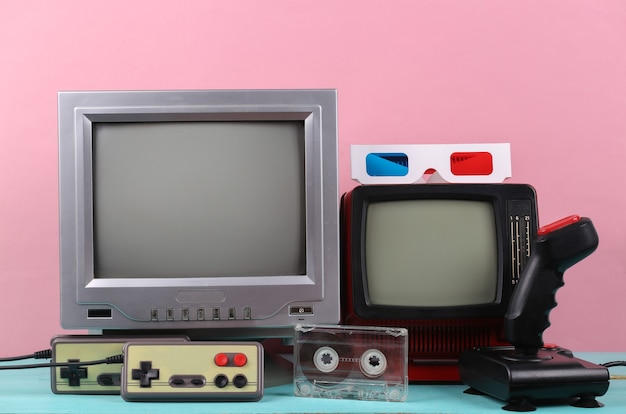 Retro portable mini tvs, joystick, gamepads, 3d glasses on pink background. Attributes 80s, retro media, entertainment